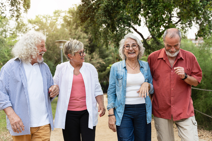 Two senior couples walking outside, socializing together